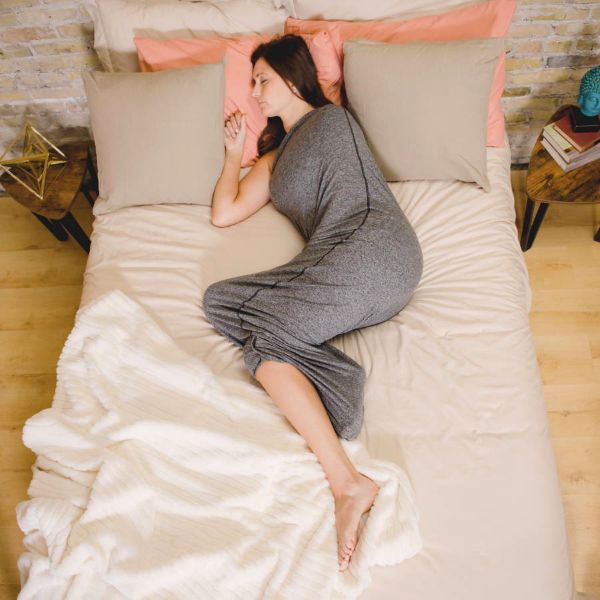 Girl on bed wearing a HugSleep resting.